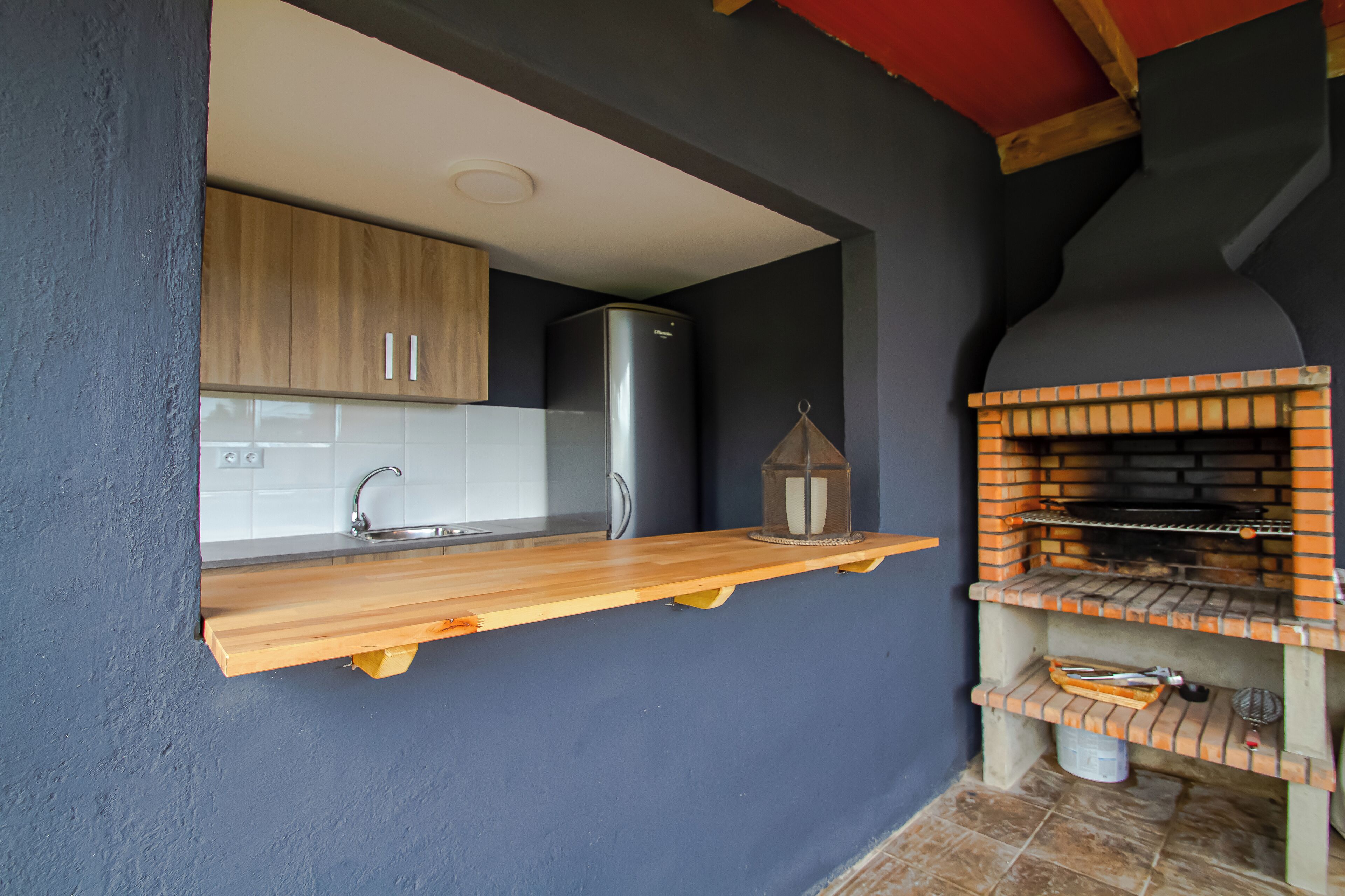 A kitchen with a wooden countertop, a stainless steel refrigerator, and a brick oven.