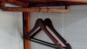 A wooden hanger rack with two hangers against a tiled wall. - DMY Guest House Nusa Penida (Penida Island)
