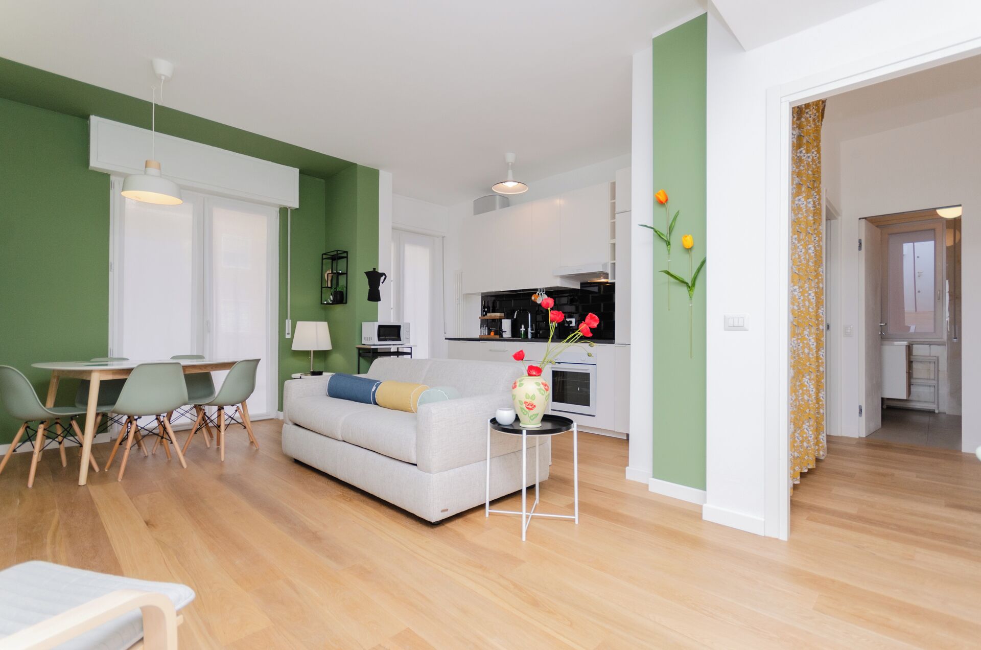 A modern living room with a white sofa, green walls, and a wooden floor.