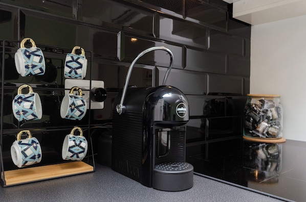 A coffee machine with a water reservoir and a display of patterned cups.
