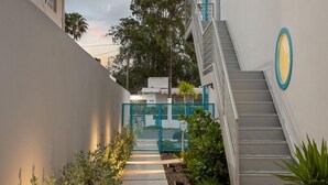 A narrow pathway flanked by buildings, a staircase, and a gated entrance.