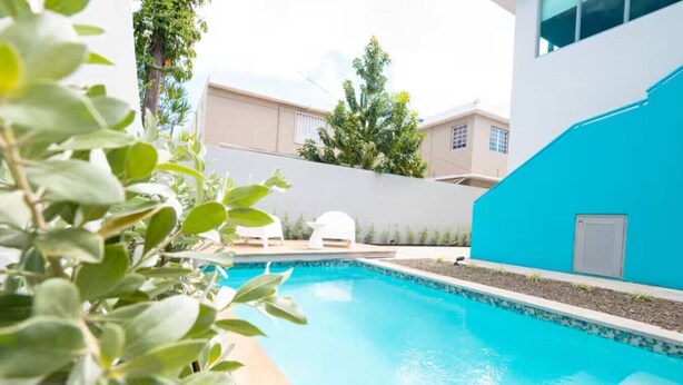 A swimming pool with a white chair and a blue wall in the background.