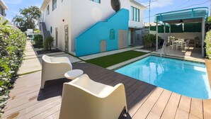 Ein modernes Haus mit Swimmingpool, Sitzgelegenheiten im Freien und einer überdachten Terrasse.