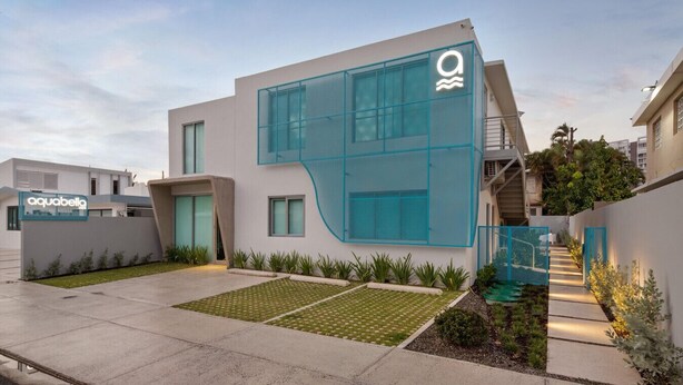 Un edificio moderno con una fachada de vidrio única y un letrero que dice 'aquabella'.