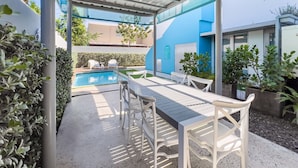 A covered outdoor area with a pool, white furniture, and potted plants. - Aquabella #6 - Tropical Escape in Isla Verde (Carolina)