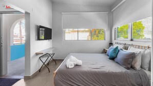 A modern bedroom with a bed, a TV, a window, and a view of the outside. - Aquabella #6 - Tropical Escape in Isla Verde (Carolina)