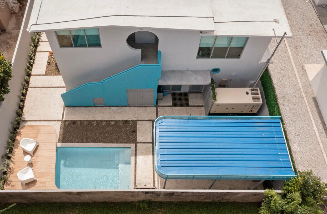 Una casa moderna con piscina, un patio cubierto y techo azul.
