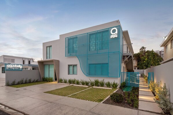 Un edificio moderno con una fachada de vidrio única y un letrero que dice 'aquabella'.