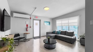 A modern living room with a sofa, a coffee table, a TV, and a plant. - Aquabella #8 - Beach Bliss in Isla Verde (Carolina)
