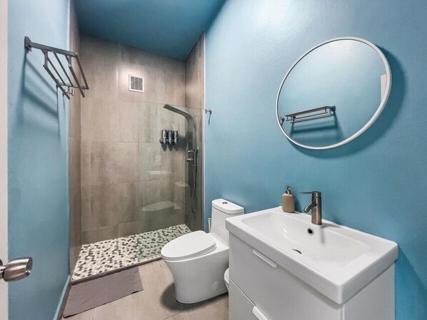 A bathroom with a shower, toilet, sink, and a mirror.