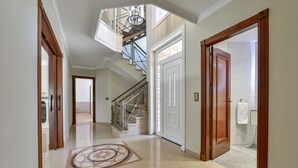 Ein geräumiger Korridor mit glänzendem Boden, einer Treppe und einer großen Tür zu einem Badezimmer.