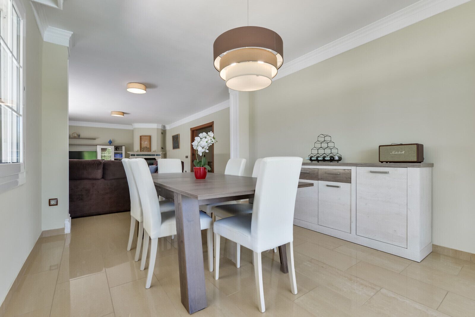 A modern dining area with a wooden table, white chairs, and pendant lighting.