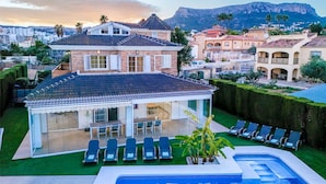 Ein Wohnhaus mit Pool, überdachter Terrasse und Blick auf ein Gebirge.