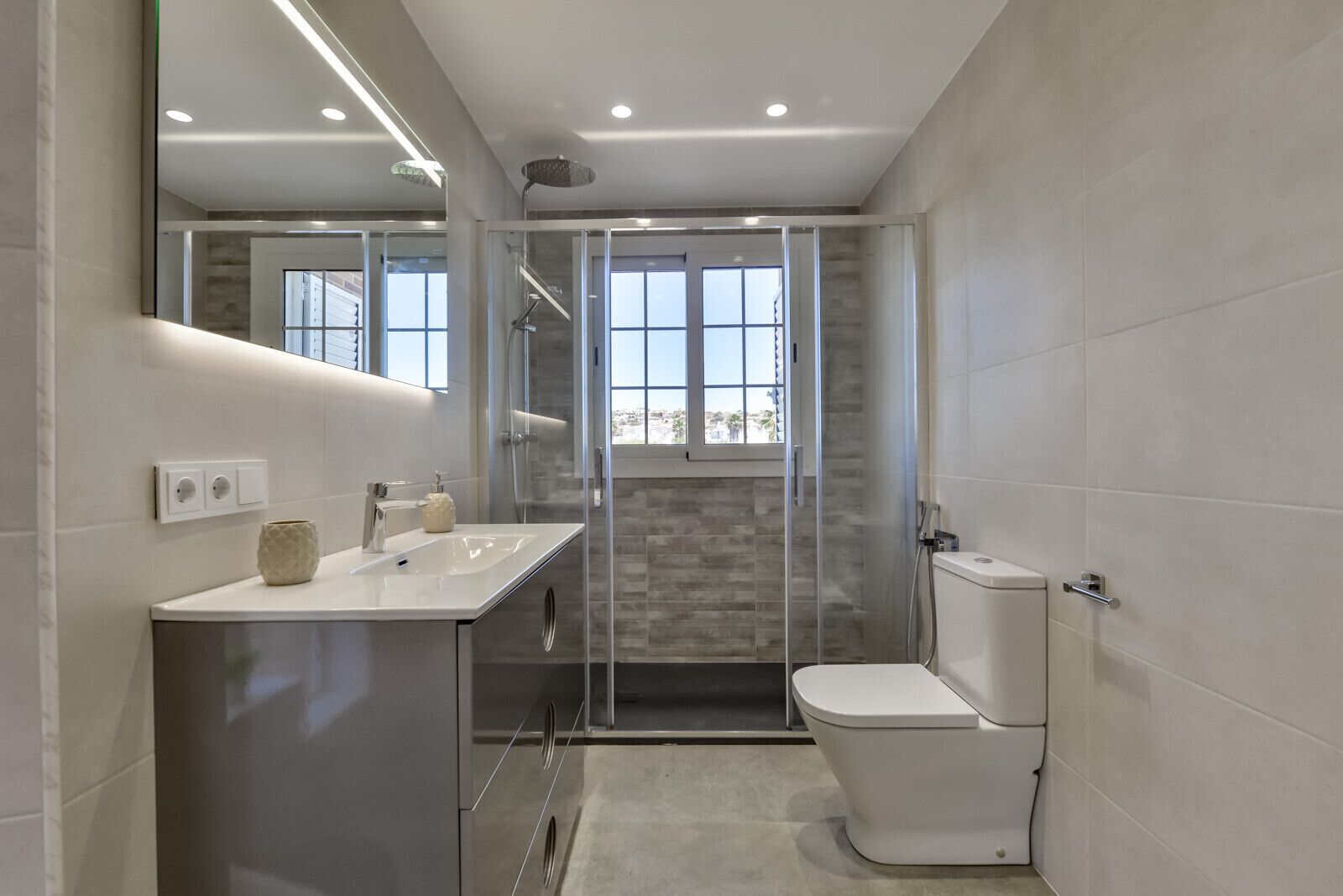 Une salle de bain moderne avec une douche à parois de verre, des toilettes et un lavabo avec un miroir au-dessus.