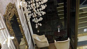 A room with a sofa, two chairs, a small table, a decorative mirror, and a hanging light fixture. - Lucid Otel (Izmir)