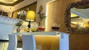 A luxurious interior with a chandelier, a sofa, a table with chairs, and a decorative mirror. - Lucid Otel (Izmir)