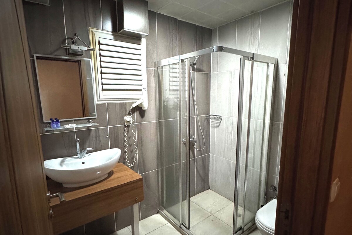 A modern bathroom with a glass-enclosed shower, a sink, and a toilet.