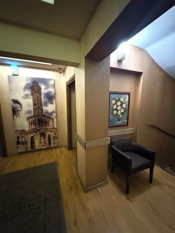 A room with a wooden floor, a chair, a wall-mounted picture, and a door. - Lucid Otel (Izmir)
