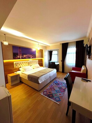 A modern hotel room with a large bed, a desk, a chair, and a small table. - Lucid Otel (Izmir)