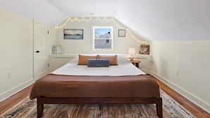 A bedroom with a large bed, a window, a door, and a ceiling light fixture. - Mountain View Cottage | Walk to Town | Pet (Shenandoah)