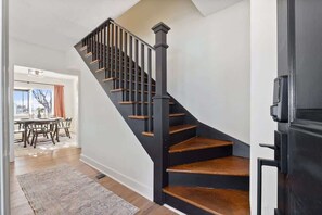 Una escalera con escalones de madera y barandillas negras que conduce a un rellano.