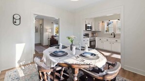 A dining room with a round table, chairs, and a chandelier. - Mountain View Cottage | Walk to Town | Pet (Shenandoah)