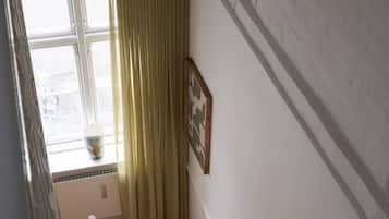 A wooden staircase with a radiator and a window with curtains.