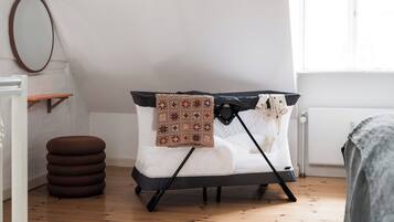 Um sofá-cama dobrável com manta estampada, um banquinho redondo e um espelho na parede.