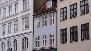 Une rangée d’immeubles à plusieurs étages aux façades blanches et grises, caractérisés par des fenêtres en arc de cercle et une variété de styles de fenêtres.