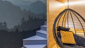 Una stanza con un murale raffigurante montagne, una poltrona sospesa e una scala.