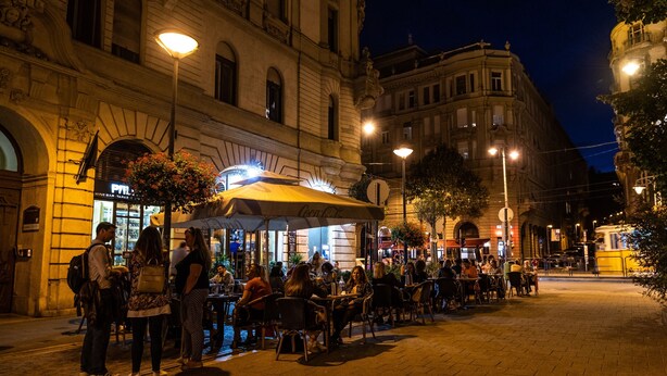 Un caffè all'aperto con tavoli e sedie, circondato da edifici storici.