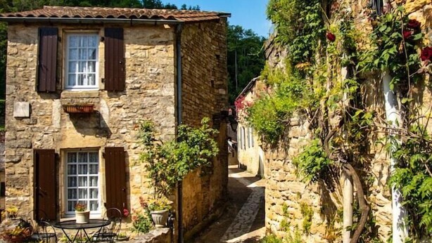 A stone building with a tiled roof, wooden shutters, and a small balcony. - Holiday Home in France with Private Terrace (Mauroux)