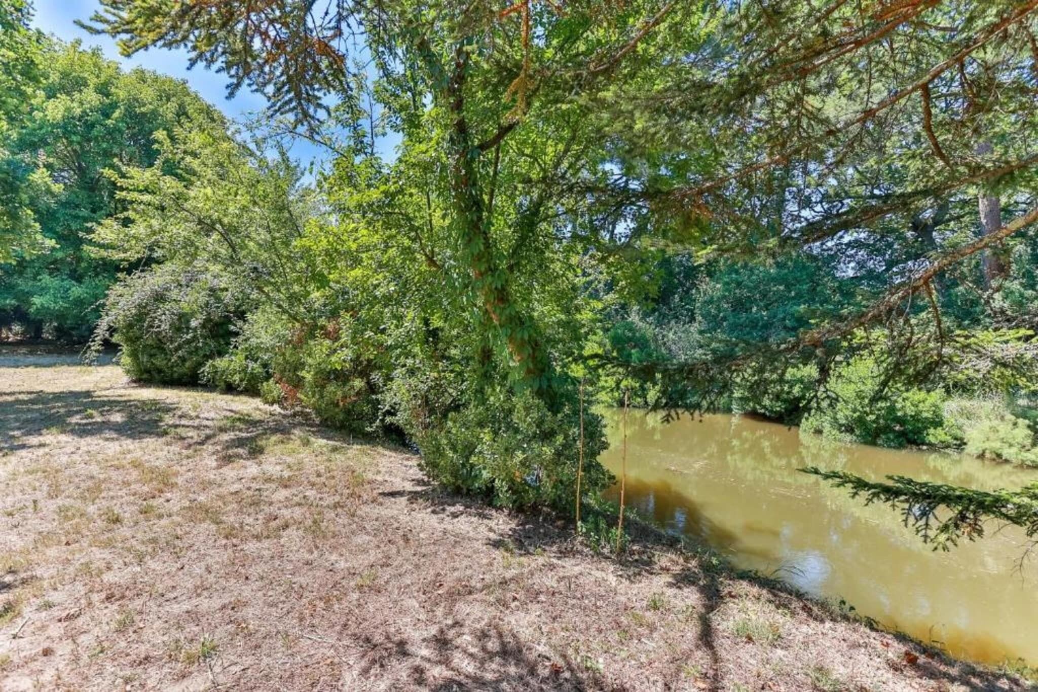 A natural landscape with a river, dense greenery, and a clear sky.