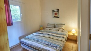 A bedroom with a bed, a nightstand with a lamp, a framed picture on the wall, and a window with curtains. - Holiday Home in France with Private Terrace (Mauroux)