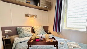 Une chambre à coucher avec un lit, une table de chevet, une commode et une fenêtre avec des rideaux.