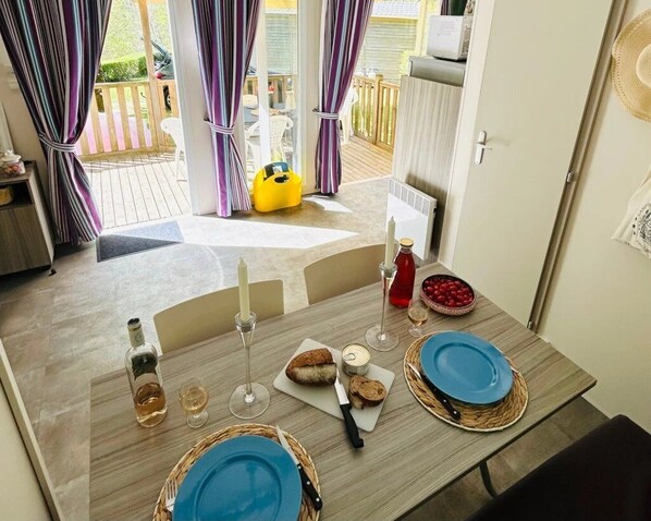 A dining table set with blue plates, a bottle of alcohol, glasses, and a basket of bread.