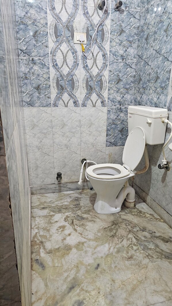 A bathroom with a toilet, a shower, and a marble-patterned wall. - Divy Dhaam Near Prem Mandir (Vrindavan)