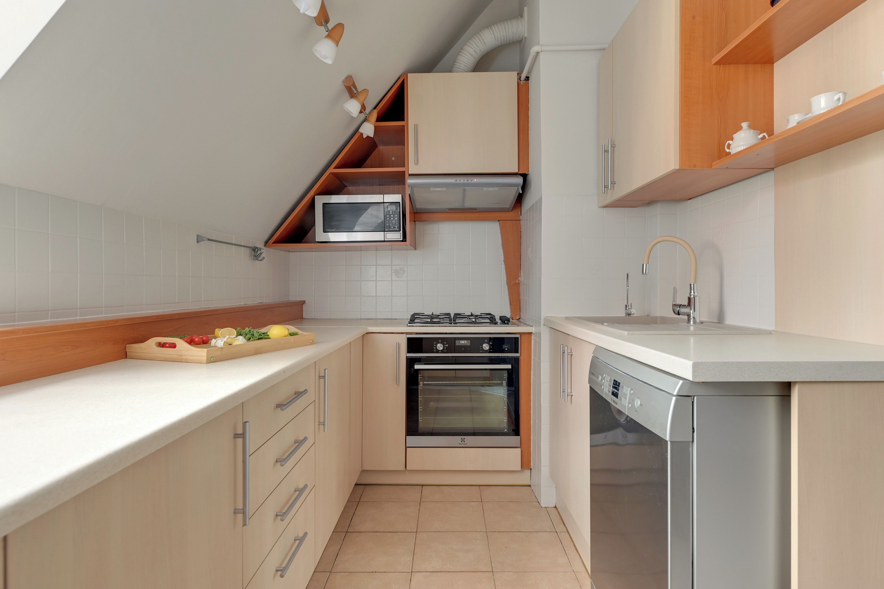 A compact kitchen with built-in appliances, wooden cabinetry, and a white countertop.