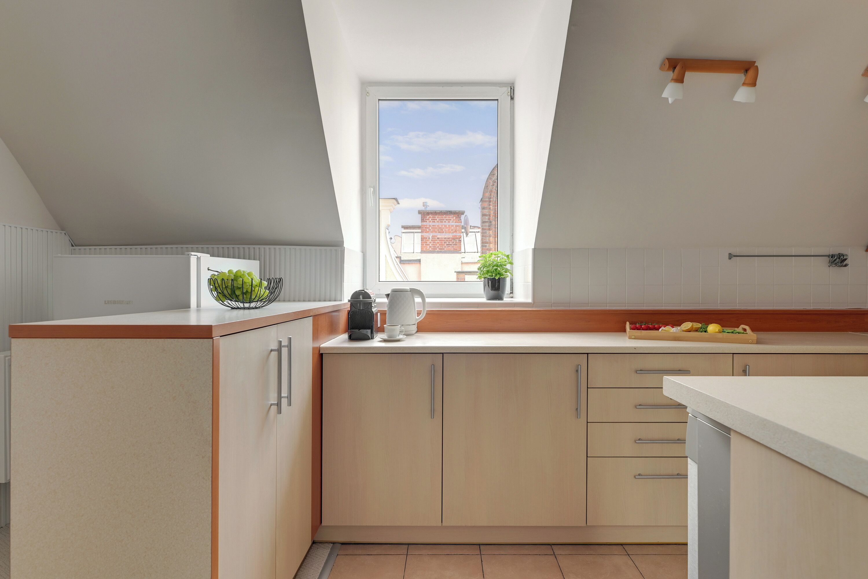 A modern kitchen with a skylight, a coffee maker, and a window with a view of buildings.