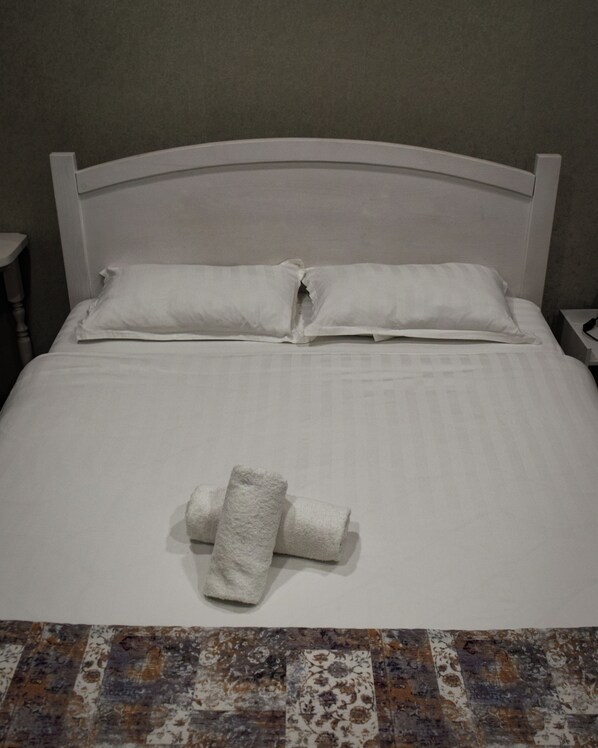 A neatly made bed with white linens and a folded towel on the bed. - Continent (Karagandy)