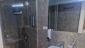 A bathroom with a glass-enclosed shower, a sink, and a mirror. - Continent (Karagandy)