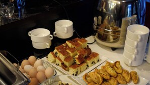 A buffet table with various food items including eggs, cereal, pastries, and a coffee station. - Continent (Karagandy)