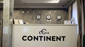 A reception desk with clocks displaying Istanbul, Mecca, and ActaHa times, and a sign reading "CONTINENT". - Continent (Karagandy)