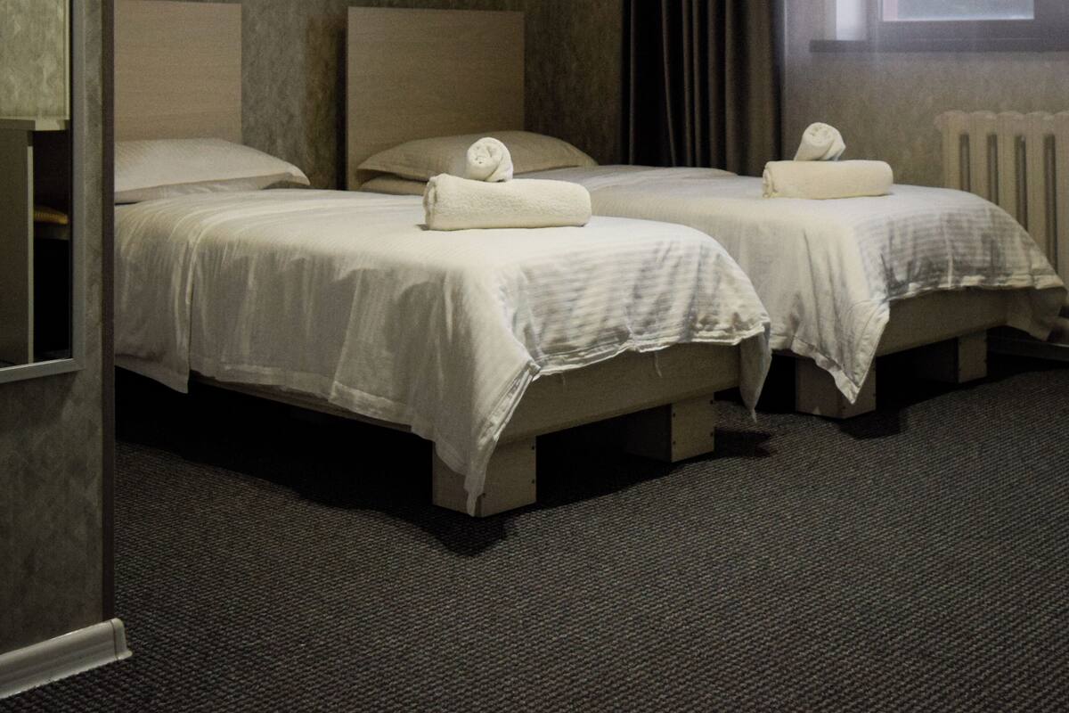 Habitación de hotel con dos camas, una ventana y un equipo de aire acondicionado.