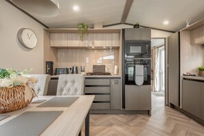 A modern kitchen with wooden cabinets, a microwave, and a built-in oven. - Lodge No 74 | Stewart's Resort Cameron (Cameron)