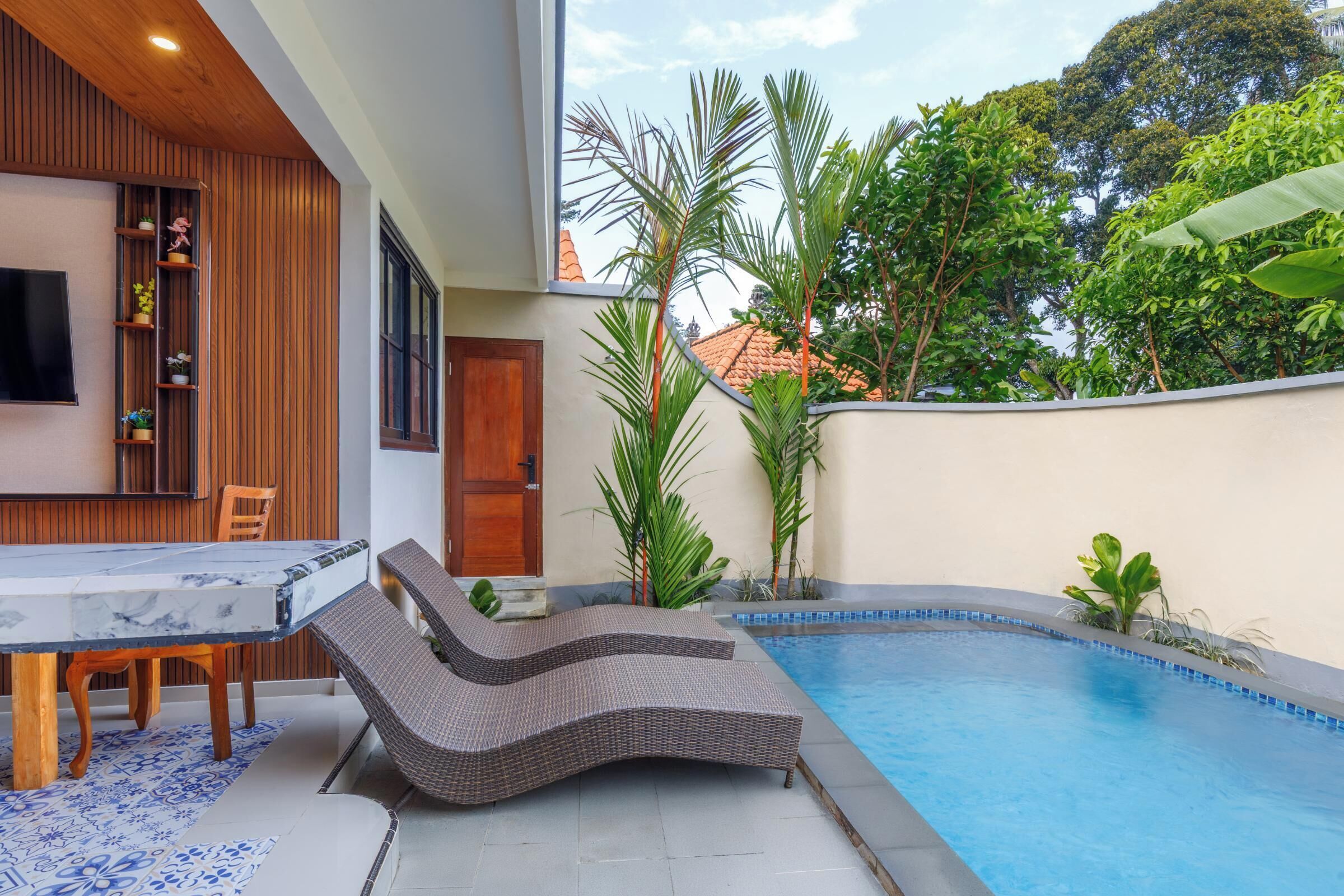A modern outdoor pool area with lounge chairs, a dining table, and potted plants.