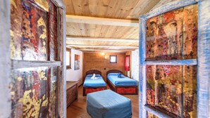A wooden room with two beds, a bench, and a small window. - Maison Chatelard (La Salle)