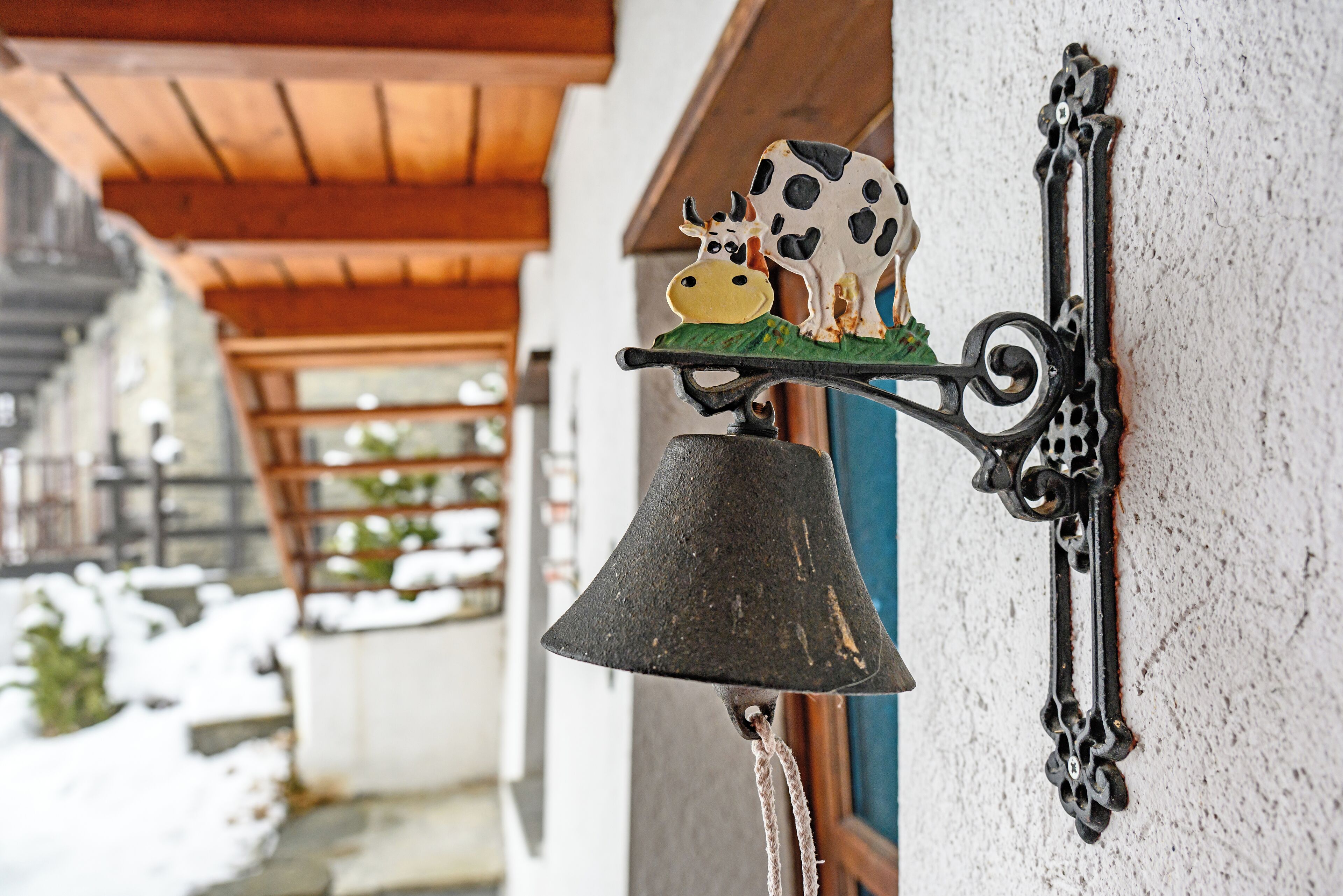 A bell mounted on a wall with a cow figurine.
