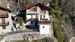A traditional chalet with stone walls, wooden balconies, and a stone staircase leading to the entrance. - Maison Chatelard (La Salle)