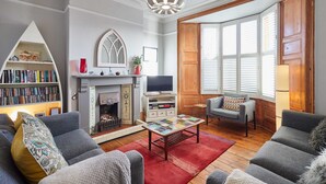A living room with a fireplace, bookshelves, a television, and comfortable seating. - Host Stay Park Terrace (Whitby)